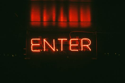Dunkler Hintergrund mit rotem Schriftzug 'Enter' als Neonlicht